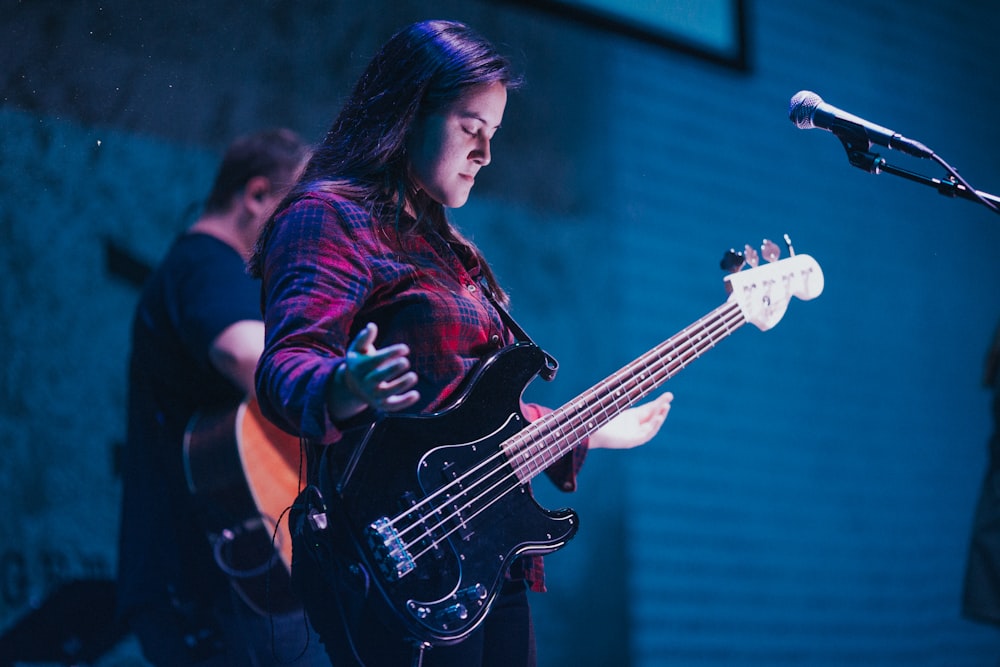 woman playing guitar near man also playing guitar