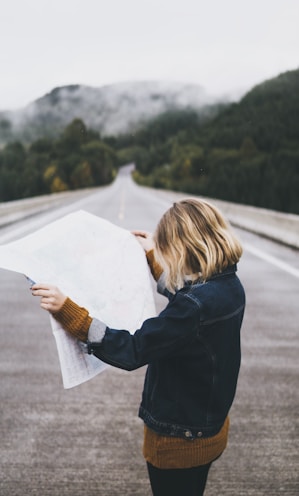 woman looking at map while standing on road