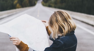 woman looking at map while standing on road