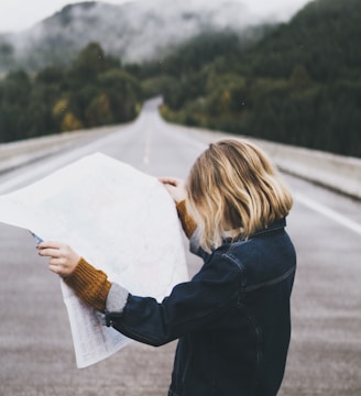 woman looking at map while standing on road