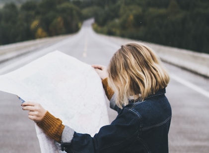 woman looking at map while standing on road