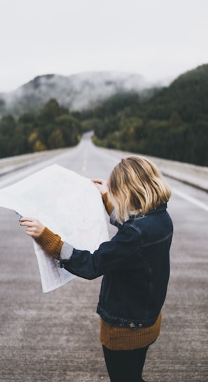 woman looking at map while standing on road