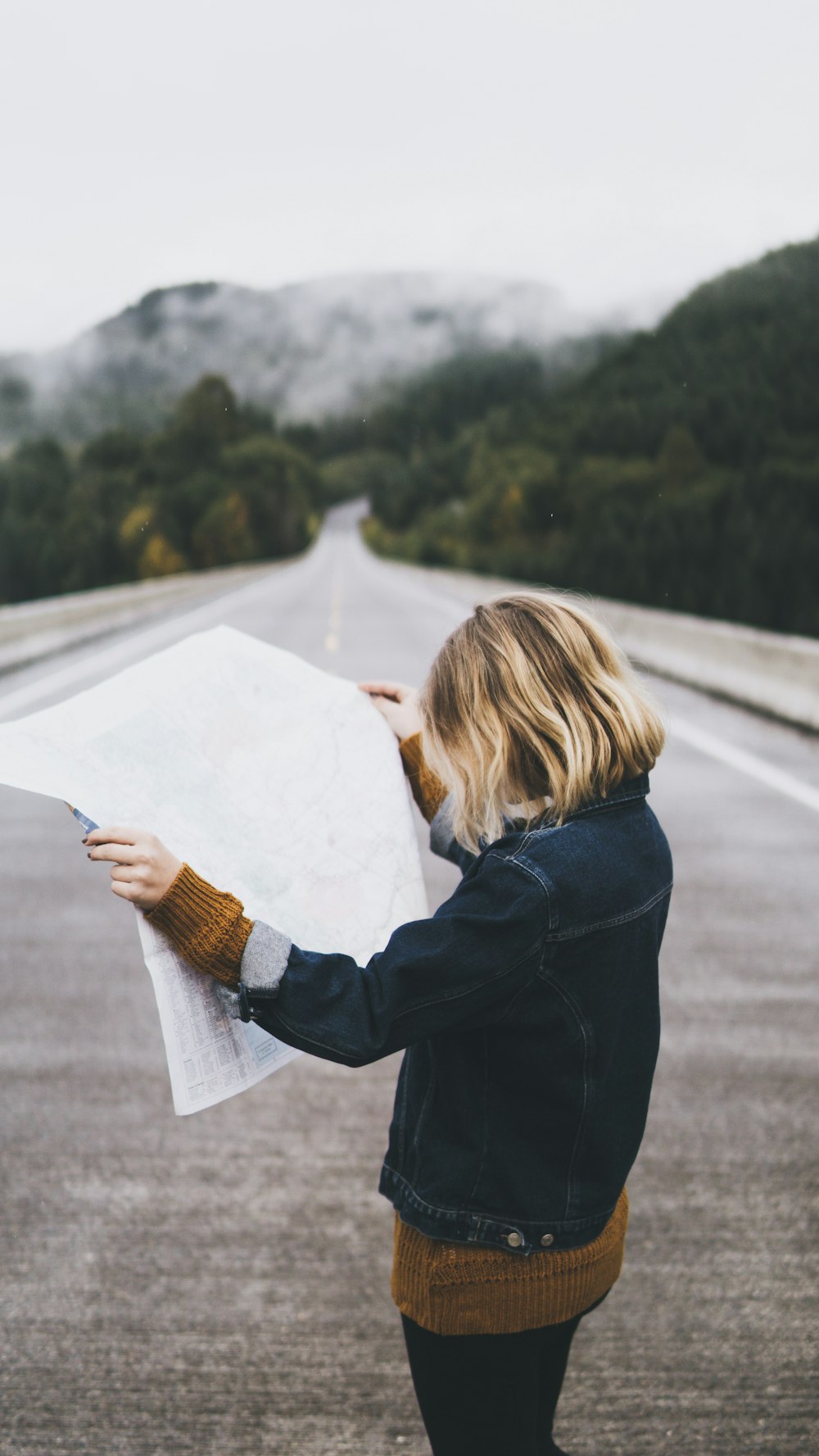 mujer mirando el mapa mientras está de pie en la carretera