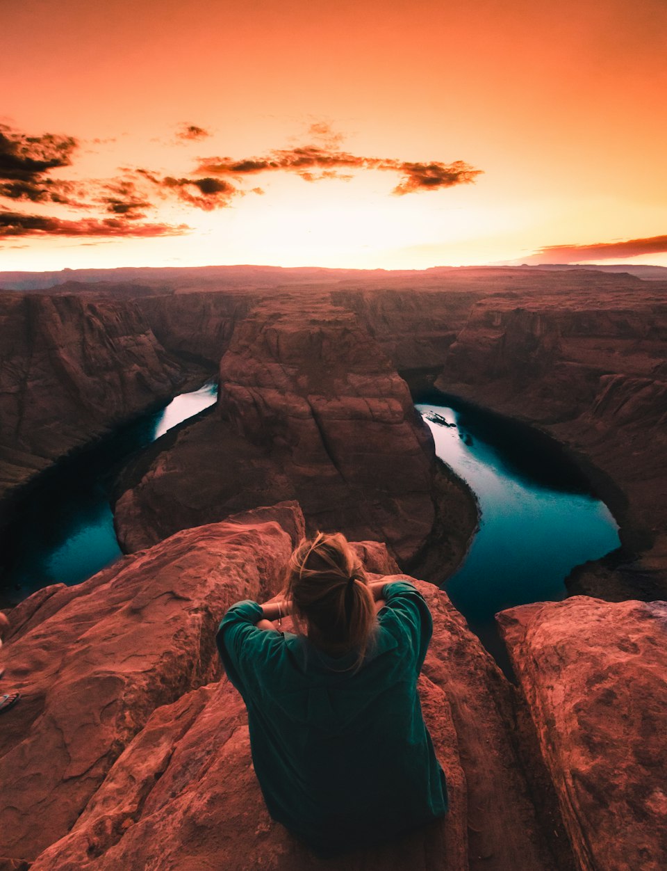 A visitor looking out over Horseshoe Bend's dramatic curve of the Colorado River at sunset