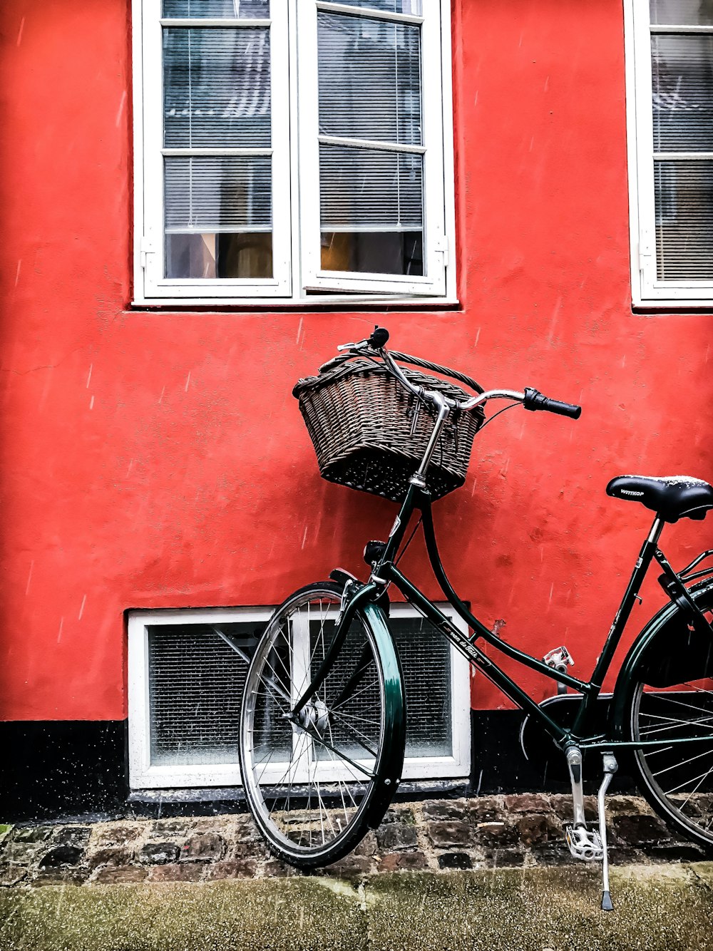 赤い壁の横の黒いクルーザー自転車