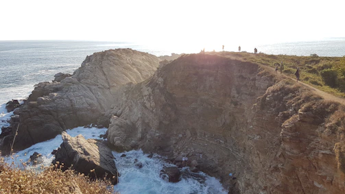 A serene coastal cliff in Albania with dramatic waves crashing below at sunset.