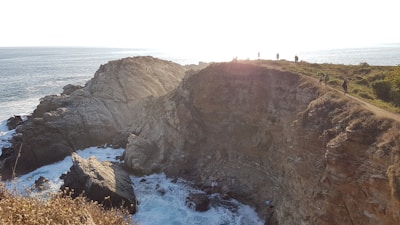 Sunset view over the rugged cliffs of a coastal trail, with waves crashing below.