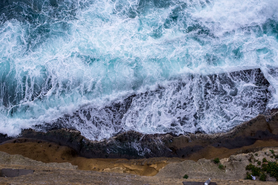 aerial view of waves crushing against rocks