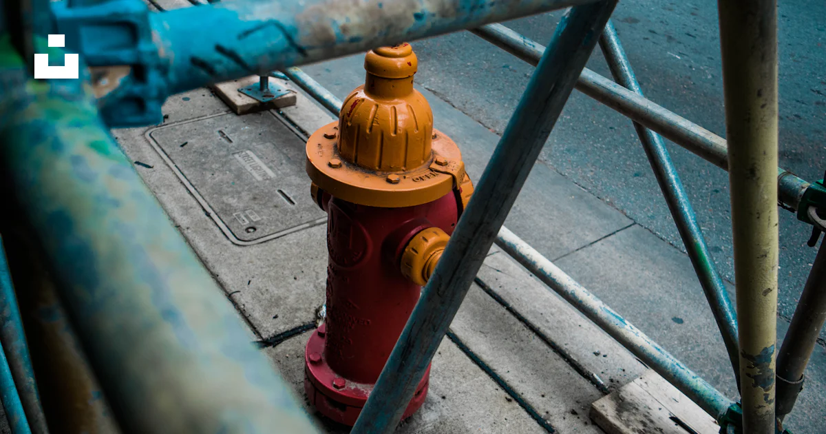 Closeup photo of orange fire hydrant covered with metal rack photo ...