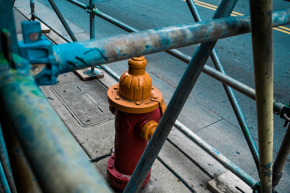 closeup photo of orange fire hydrant covered with metal rack
