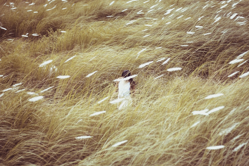 femme portant une robe debout sur le sol et entourée d’herbe