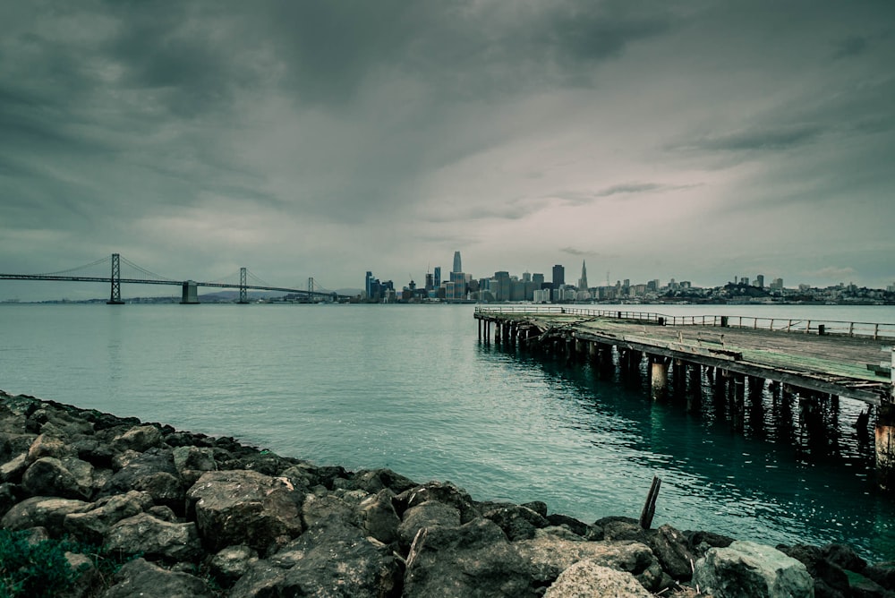 gray concrete sea dock near city under white clouds during daytime