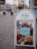 A street advertisement signboard displays the brand 'Paulig' and features an image of Taiyaki, which is a fish-shaped Japanese street food pastry, positioned on a city sidewalk with a backdrop of urban traffic and illuminated trees.