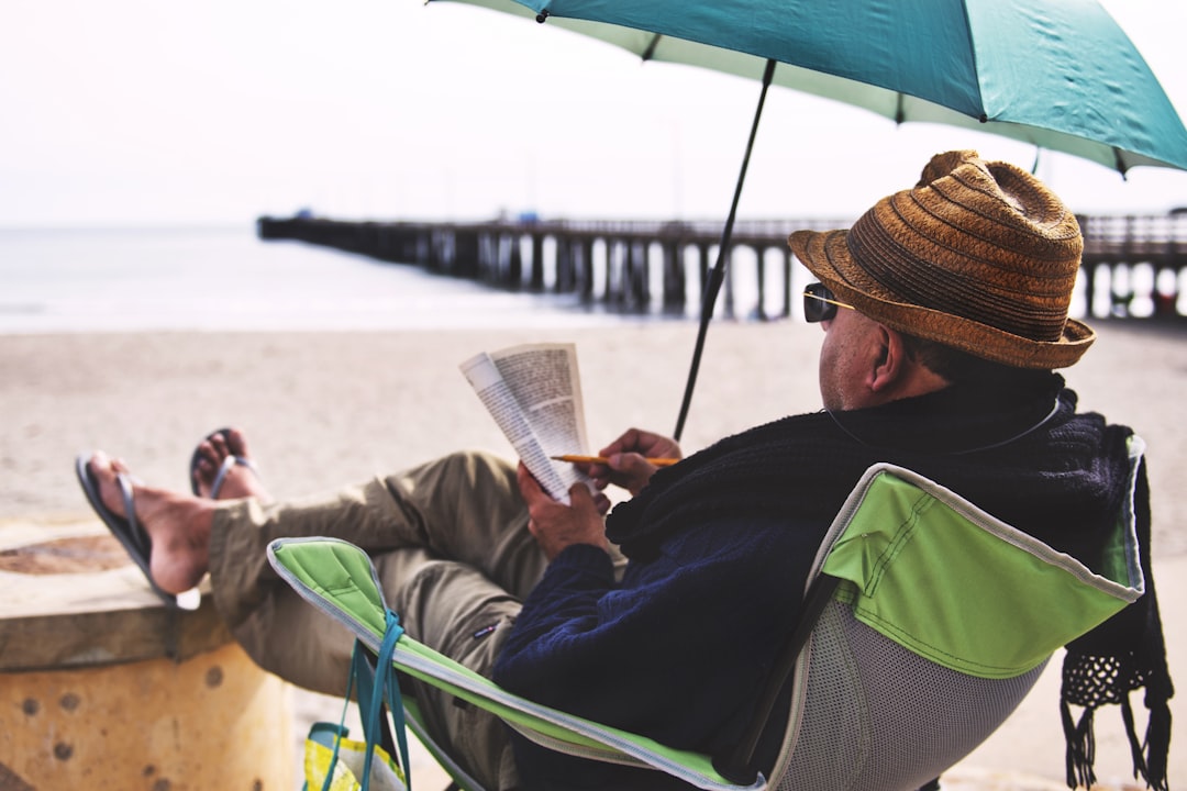 man sitting on chair with green umbrella, Winter Beach Days