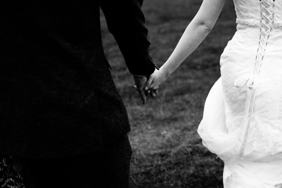 A sleek black and white photo of a wedding couple holding hands, symbolizing connection and trust.