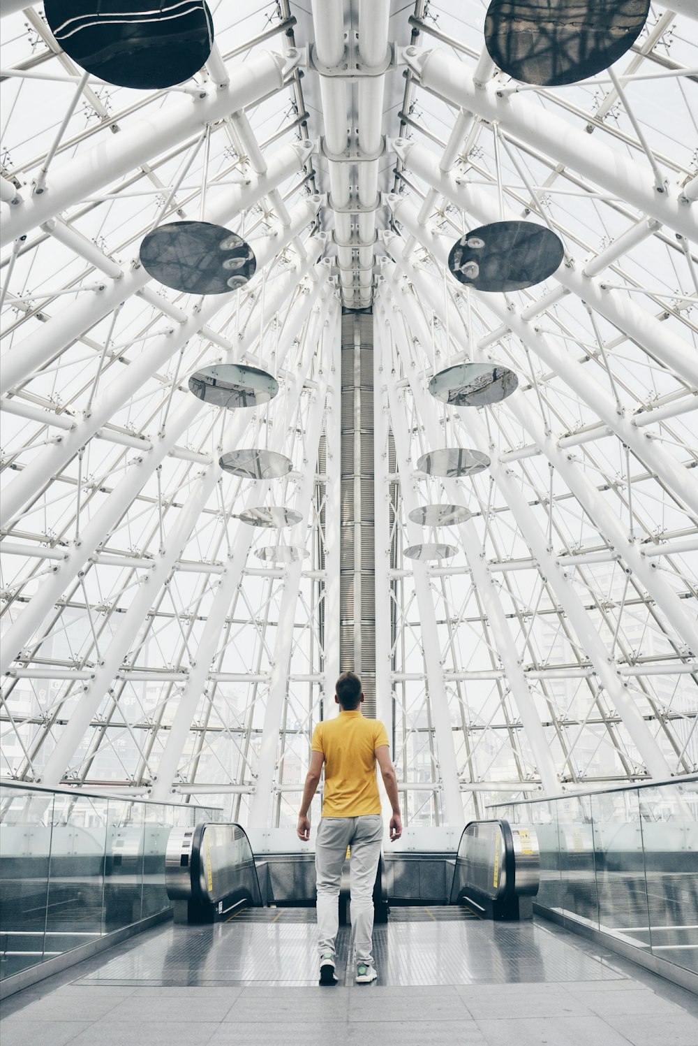 man standing under glass panel dome during daytime