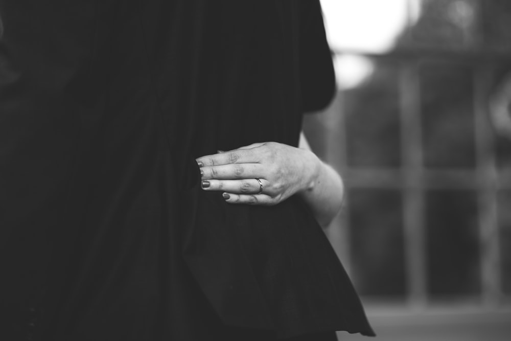 person holding apparel in grayscale photography
