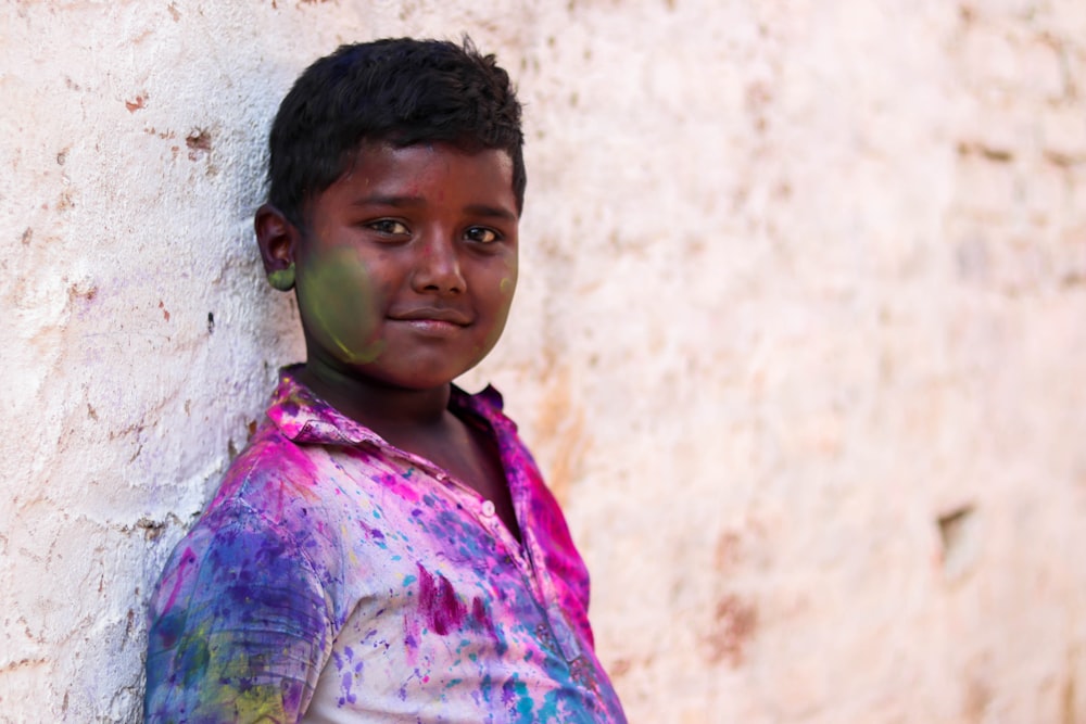 boy leaning on white wall at daytime