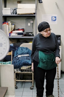 woman wearing gray top and black pants walking using walking cane