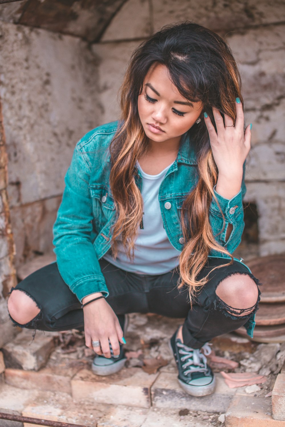 woman sitting near gray and brown concrete wall during daytime