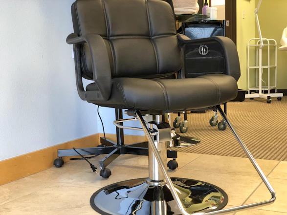 Minimalistic black leather salon chair beside a large mirror with soft natural light.
