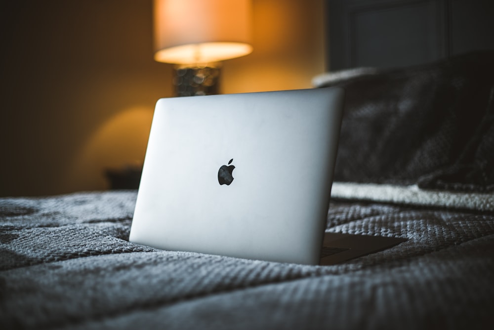 A refurbished Apple Macbook open on a bed.