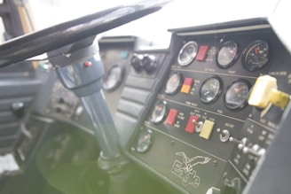 A close-up view of a vehicle dashboard with multiple gauges, switches, and indicators. A steering wheel is prominently visible, and there is branding with the word 'Eagle' and an eagle graphic. The dashboard includes dials for air pressure, fuel, and other metrics, with a variety of buttons and colored labels.