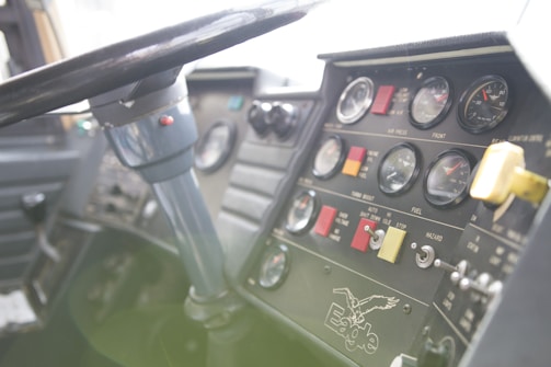 A close-up view of a vehicle dashboard with multiple gauges, switches, and indicators. A steering wheel is prominently visible, and there is branding with the word 'Eagle' and an eagle graphic. The dashboard includes dials for air pressure, fuel, and other metrics, with a variety of buttons and colored labels.