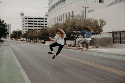 two woman jumping on the street during daytime cheerful teams background
