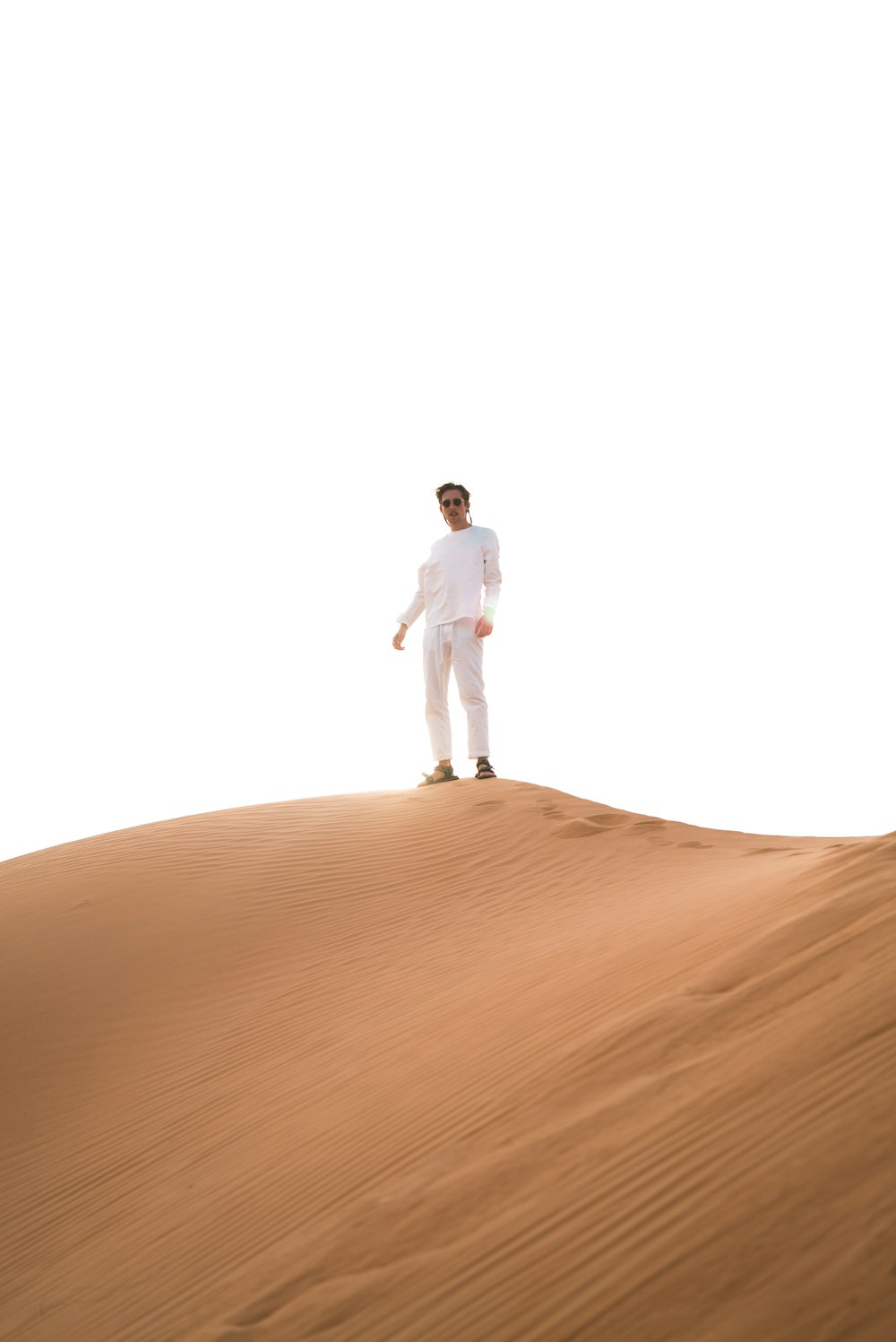 man standing atop desert sand dune