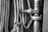 A monochrome image featuring a coiled fire hose alongside a metallic pipeline and valve. The valve has a round handle and appears to be an integral part of an industrial or mechanical setting.