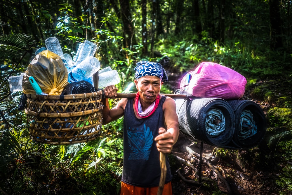 person carrying basket with plastic bottles surrounded by trees