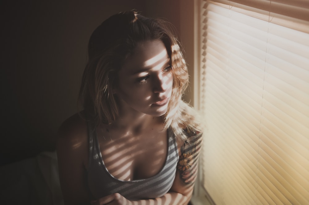 woman looking through window blinds