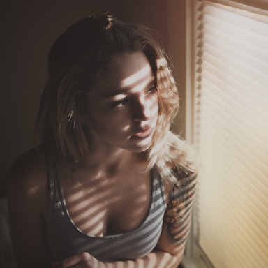 woman looking through window blinds