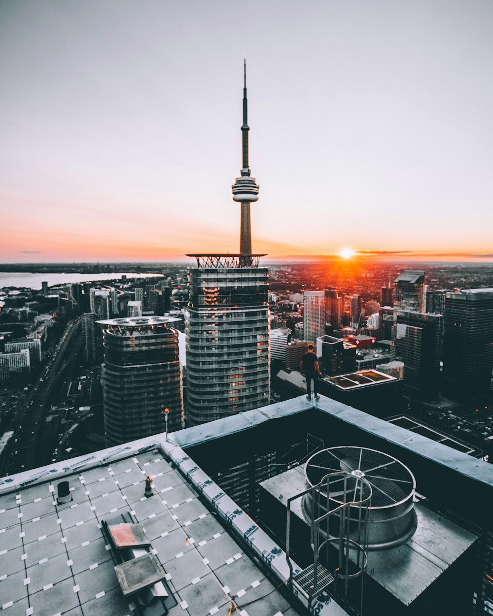 Person, die während des Sonnenuntergangs auf dem Dach des Gebäudes vor dem CN-Turm steht