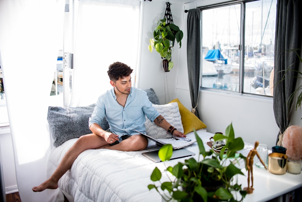 man sitting on bed near window