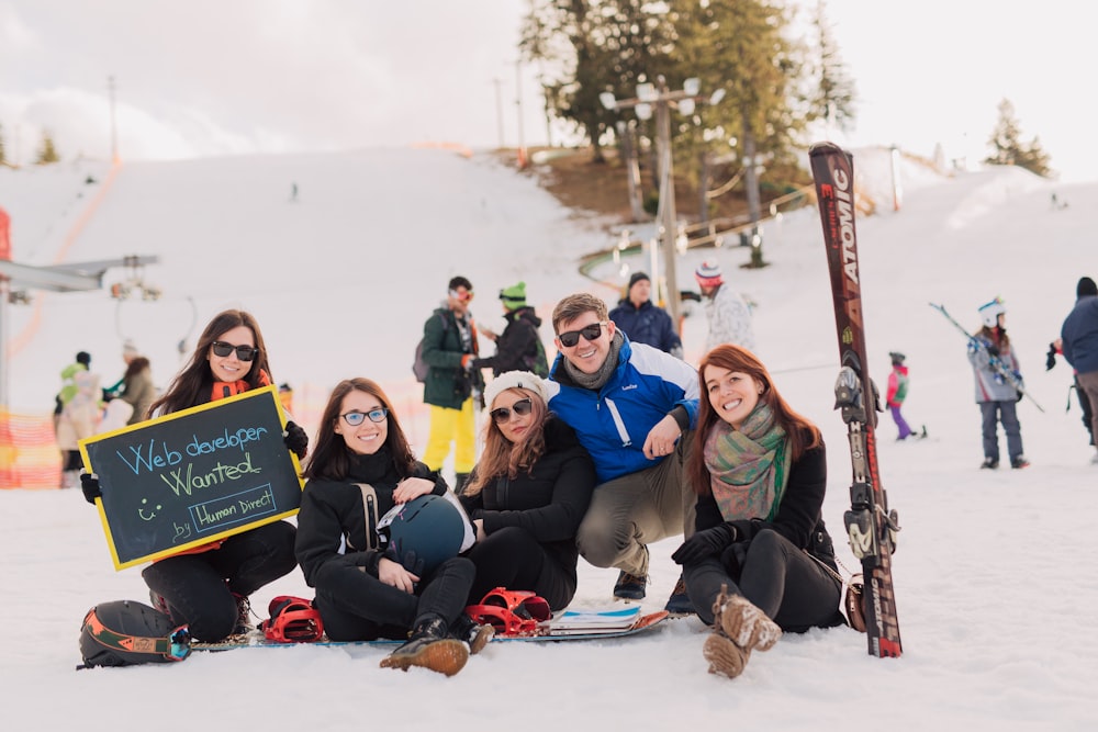 gruppo di persone che si siedono sulla neve che scattano foto