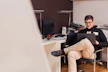 A smiling young man working on a laptop in a cozy home office.