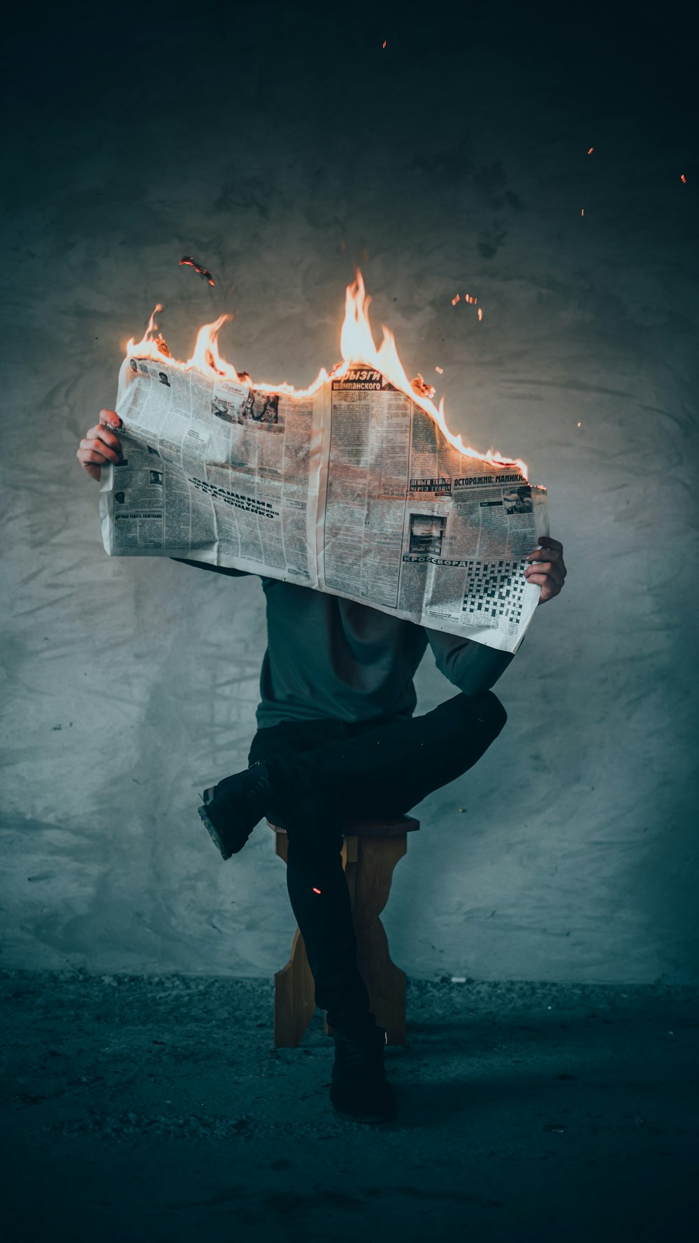 surrealism photography of person reading news paper in fire while sitting on stool