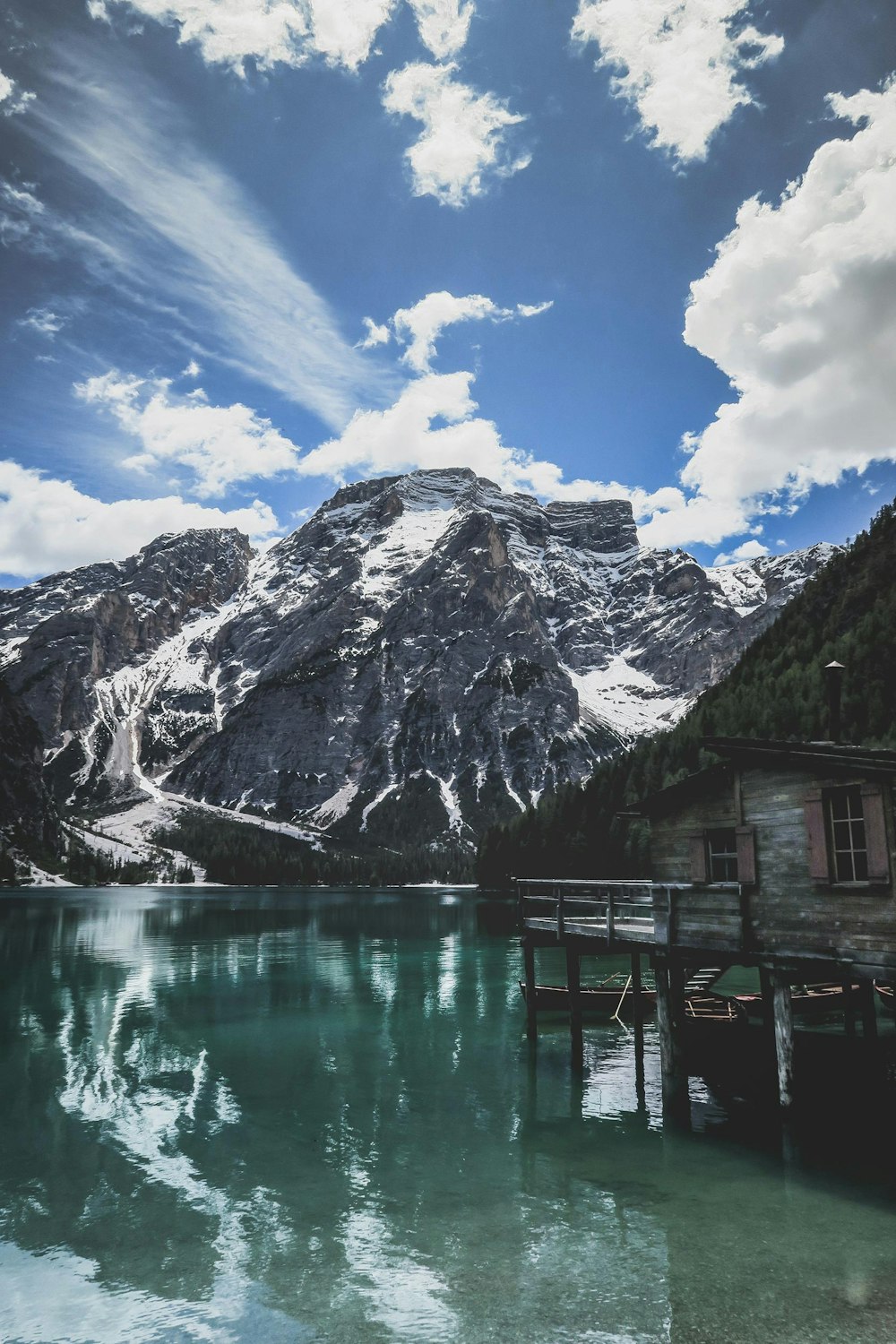 Cottage di legno grigio sullo specchio d'acqua vicino alla montagna