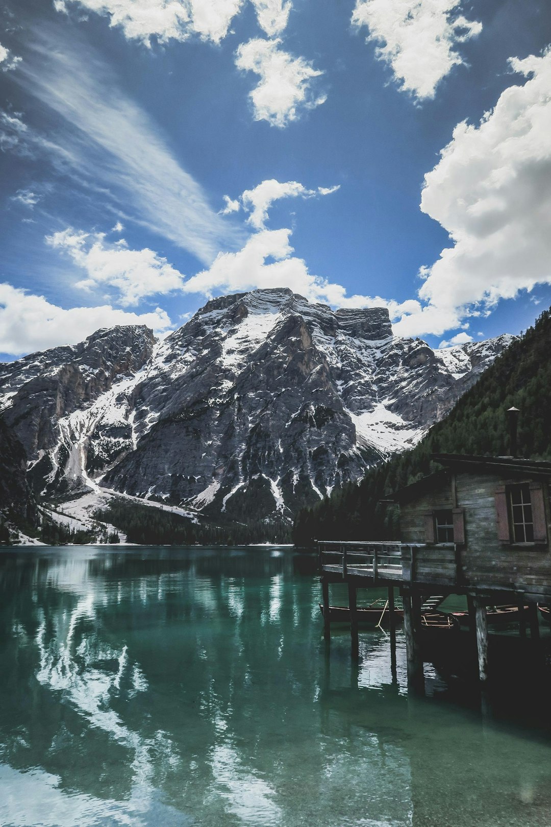 gray wooden cottage on body of water near mountain