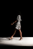 woman wearing black and white floral dress walks inside dark room