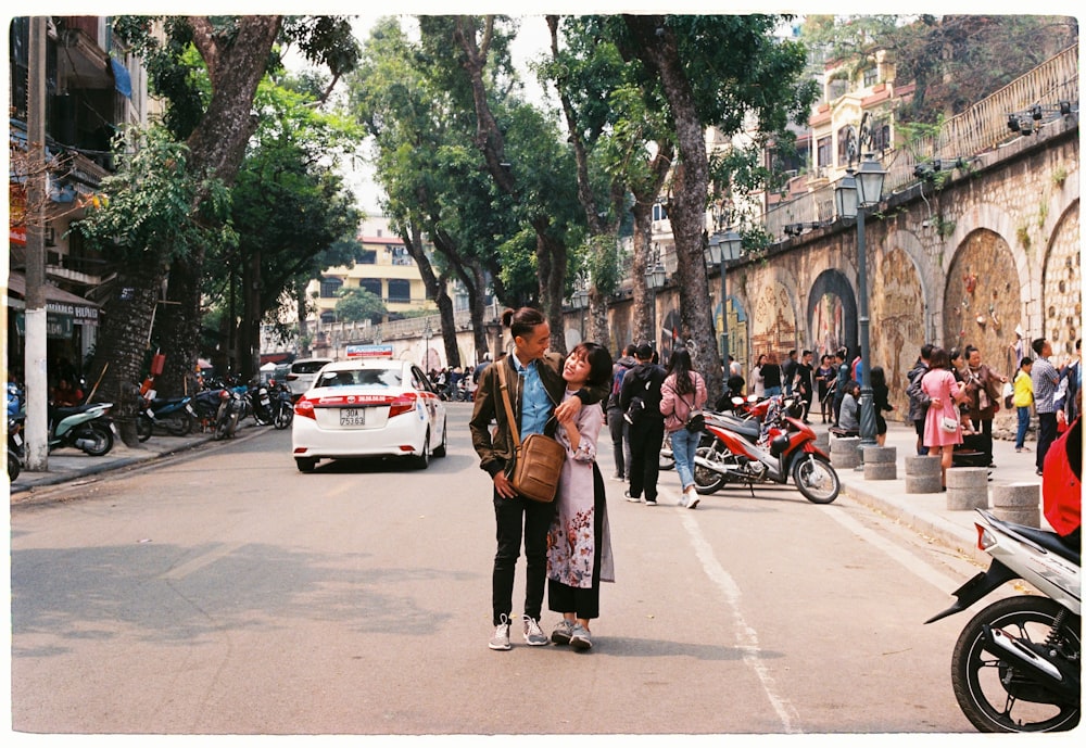 man and woman standing on the street while hugging each other