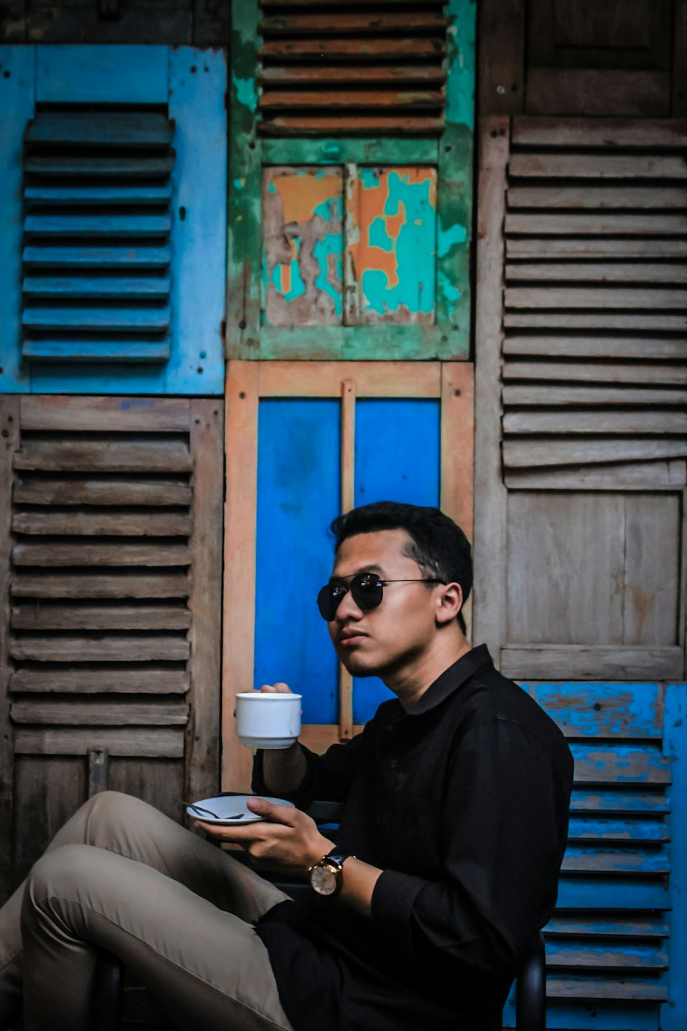 man in black dress shirt holding saucer and mug