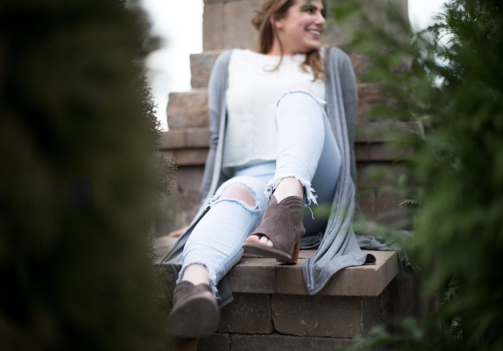 a woman sitting on top of a brick wall