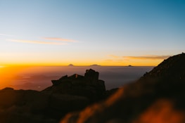 Sunset over mountain peaks with a silhouette of a climber.