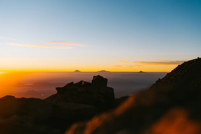 Sunset over a misty mountain range in Central Asia with a lone traveler silhouette.