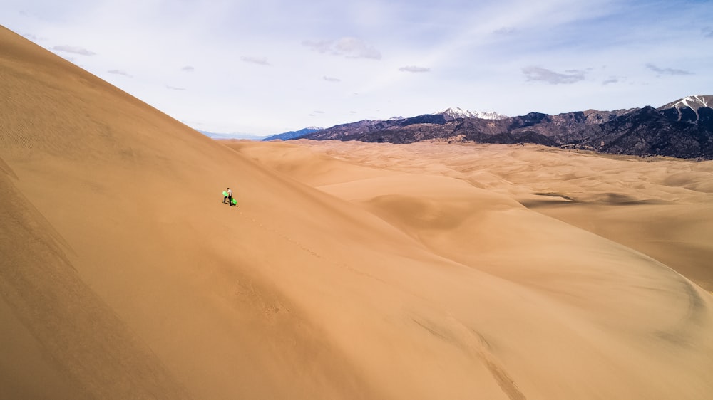 person sits on desert under clear blue sky during daytime