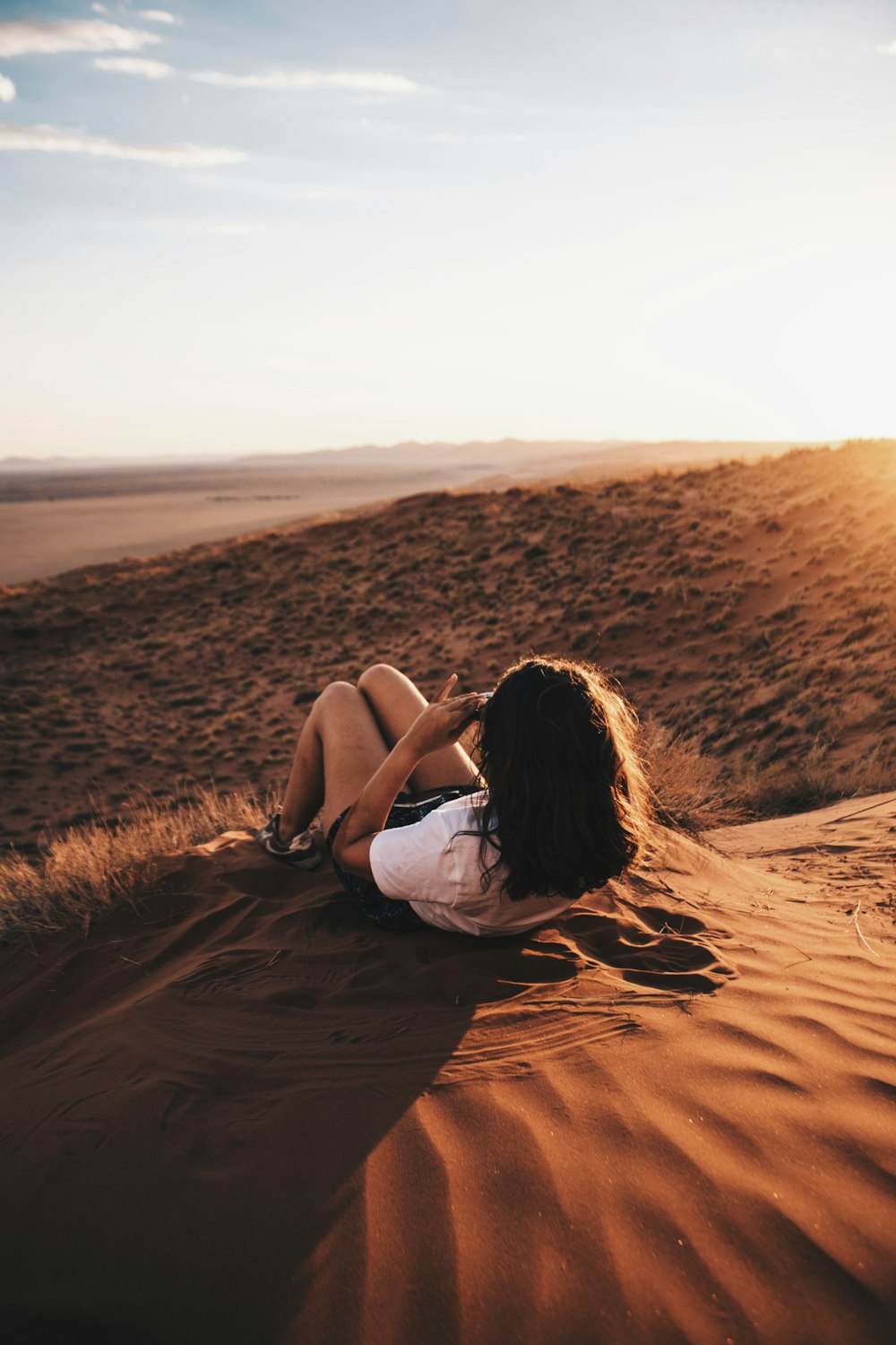 woman lying on sand during daytime