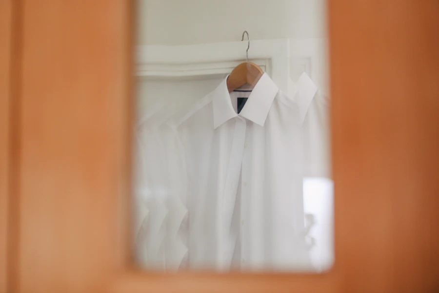 Une chemise blanche immaculée suspendue à un cintre, fond clair et lumière douce